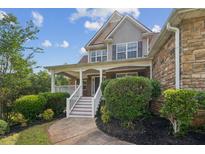 Charming two-story home featuring a covered front porch, landscaped yard, and stone and siding exterior at 167 Gothards Creek Dr, Powder Springs, GA 30127