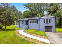 Charming home featuring a blue painted brick exterior, well-manicured lawn, and an attached one-car garage at 3211 Hollydale Drive Sw, Atlanta, GA 30311