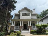 Charming two-story home featuring a welcoming front porch with brick and white pillars and landscaped yard at 2552 White Oak Dr, Decatur, GA 30032