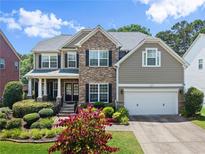Charming two-story home featuring a stone facade, manicured landscaping, and a welcoming front porch at 4665 Idlewood Dr, Cumming, GA 30040