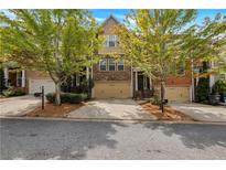 Inviting brick townhome featuring a 2-car garage and well-maintained landscaping at 630 Birch River Ln, Lawrenceville, GA 30043