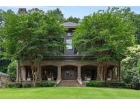 Elegant brick home featuring a covered front porch, manicured lawn, and mature trees at 1640 Nottingham Ne Way, Atlanta, GA 30309