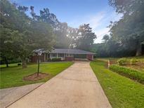 Charming single-story home with long driveway and mature trees on a sunny day at 2584 Favor Sw Rd, Marietta, GA 30060