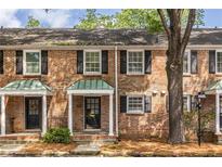 Traditional brick townhouse featuring black shutters, covered entryway, and professional landscaping at 6700 Roswell Rd # 21E, Sandy Springs, GA 30328