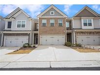 Charming townhome exterior featuring brick and gray siding, a two-car garage, and a well-maintained driveway at 5316 Radford Loop, Fairburn, GA 30213