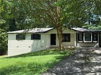 Charming one-story home with a well-maintained front yard and a classic brick facade, shaded by mature trees at 2095 Mulkey Sw Rd, Marietta, GA 30008