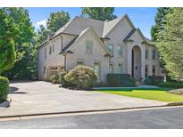Stunning two-story brick home with a well-manicured lawn and a long driveway leading to a two car garage at 8430 Merion Drive, Duluth, GA 30097