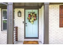 Charming front door features a teal door with a floral wreath and a brick surround, enhancing curb appeal at 3093 Del Monico Dr, Decatur, GA 30032