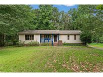 Charming single-story home with a well-maintained lawn and inviting front porch with distinct blue railing at 137 Trickum Hills Dr, Woodstock, GA 30188