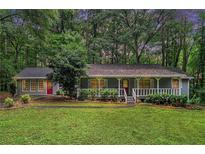 Charming single-story home with a welcoming front porch and a lush green lawn surrounded by mature trees at 5317 Highway 81, Loganville, GA 30052