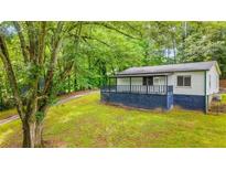Charming home with blue skirting, covered porch, and lush greenery at 1841 Mobley St, Austell, GA 30106