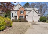 Charming two-story home featuring a brick facade, attached two-car garage, and a well-manicured lawn at 7335 Treyland Ct, Cumming, GA 30041