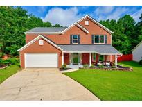 Charming two-story brick home featuring a well-manicured lawn and an attached two-car garage at 5388 Silver Springs Dr, Sugar Hill, GA 30518