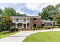 Charming brick home featuring a lovely front porch, second-story balcony, and well-manicured lawn at 4047 Dunwoody Club Dr, Dunwoody, GA 30350