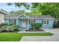 Charming blue house with a well-maintained lawn, garden and welcoming front porch at 877 Mclendon Dr, Scottdale, GA 30079