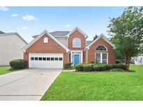 Charming two-story brick home with a well-manicured lawn and a bright blue front door at 1460 Chamirey Sw Dr, Marietta, GA 30008