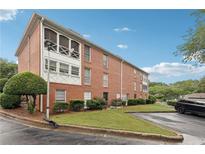 Brick condo building featuring a screened in porch, manicured lawn, and well-maintained landscaping at 1166 Booth Sw Rd # 301, Marietta, GA 30008
