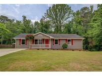 Charming single-story home featuring a landscaped lawn and a welcoming front porch with red door and shutters at 170 Hidden Pines Dr, Covington, GA 30016
