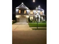 Two-story home featuring beautiful exterior lighting, a manicured lawn, and attached garage at 1730 Dahlia Dr, Cumming, GA 30040