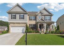 Charming two-story home featuring brick, stone accents, a manicured lawn, and an attached two-car garage at 1730 Dahlia Dr, Cumming, GA 30040