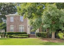 Charming brick home featuring a well-manicured lawn, mature trees, and a welcoming entrance at 6057 Glencedar Ln, Atlanta, GA 30349