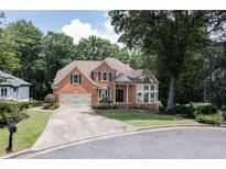 Charming two-story brick home with a well-manicured lawn and attached two-car garage at 6185 Masters Club Dr, Suwanee, GA 30024