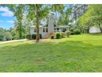 Charming home features lush green lawn, mature trees, and a welcoming front entrance at 6918 Heritage Pl, Acworth, GA 30102