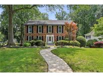 Charming two-story brick home with mature trees and a well-manicured lawn at 100 Spring Ridge Ct, Roswell, GA 30076