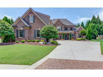 Stately brick home with manicured lawn, mature trees, and a spacious driveway leading to a welcoming entrance at 120 Slate Dr, Buford, GA 30518