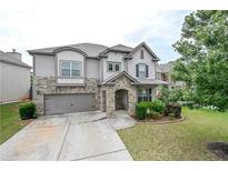 Charming two-story home with stone accents, well-manicured lawn, and an attached two-car garage at 3291 Meadow Lily Ct, Buford, GA 30519
