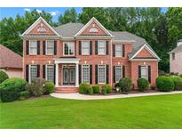 Elegant brick home with a manicured lawn and lush landscaping at 871 Windsor Creek Dr, Grayson, GA 30017