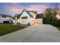 Charming home features a modern farmhouse design with white brick, black trim and a spacious driveway at 6750 Pannell Rd, Buford, GA 30518