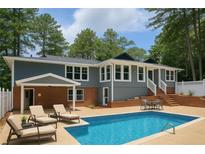 Back exterior of a home with a pool, lounge chairs, and a patio seating area, perfect for outdoor relaxation at 1516 Chase Ct, Riverdale, GA 30296