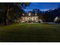 Inviting two-story home with a sprawling lawn, covered porch, and manicured landscaping at twilight at 654 Cannon Rd, Sharpsburg, GA 30277