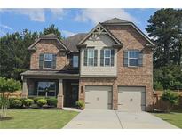 Charming brick two-story home featuring a two-car garage, inviting front porch, and manicured lawn at 2311 Arnold Palmer Way, Duluth, GA 30096