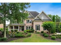 Charming two-story brick home with a well-manicured lawn and lush landscaping at 2430 Flat Stone Dr, Cumming, GA 30041