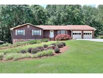 Charming single-story home boasts a well-manicured lawn, mature trees, and a two-car garage at 1123 Willow Trce, Grayson, GA 30017
