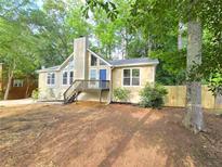 Charming home showcasing a front deck, neutral siding, complemented by a backdrop of mature trees and natural landscaping at 2489 Smith Ave, Marietta, GA 30064