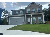 Charming two-story home featuring brick and gray siding, a two-car garage, and a well-manicured lawn at 495 Sterling Creek Way, Loganville, GA 30052