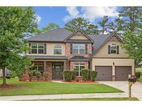 Charming two-story home featuring a well-manicured lawn, brick accents, and a two-car garage at 8398 Members Dr, Jonesboro, GA 30236