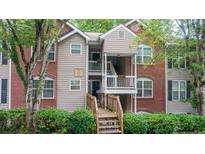 Charming condo featuring a brick and siding exterior, a wooden porch, and lush landscaping at 434 Teal Ct, Roswell, GA 30076