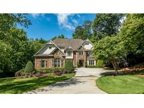 Elegant brick and stone two-story home with a manicured lawn and a circular driveway at 5284 Vernon Springs Nw Trl, Sandy Springs, GA 30327