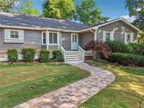 Charming home with brick walkway, gray siding, white trim, and lush landscaping at 2655 Nesbit Trl, Alpharetta, GA 30022