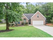 Charming brick home featuring a well-manicured lawn, mature trees, and a two-car garage at 7720 Paddocks Mill Dr, Cumming, GA 30041