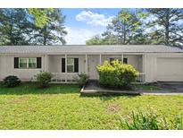 Charming one-story home with a covered front porch and well-maintained landscaping in a lush, green lawn at 1799 Harmony Rd, Powder Springs, GA 30127