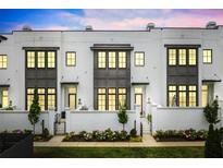 Inviting townhouse showcases a white brick facade, complemented by elegant gray window frames and manicured landscaping at 6640 Avis Walk, Alpharetta, GA 30005