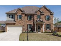 Traditional two-story brick home with well-manicured front lawn and a two car garage at 7435 Ansley Park Way, Cumming, GA 30028