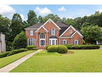 Beautiful two-story brick home featuring a well-manicured lawn and mature landscaping at 2613 Winterthur Main Nw, Kennesaw, GA 30144
