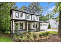 Charming two-story modern farmhouse with black trim, front porch, white siding and a beautifully landscaped front yard at 2638 Clairmont Rd, Atlanta, GA 30329