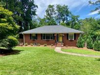 Charming brick home with a well-manicured lawn, flower boxes, and a welcoming yellow front door at 406 S Hillcrest Sw Dr, Marietta, GA 30064